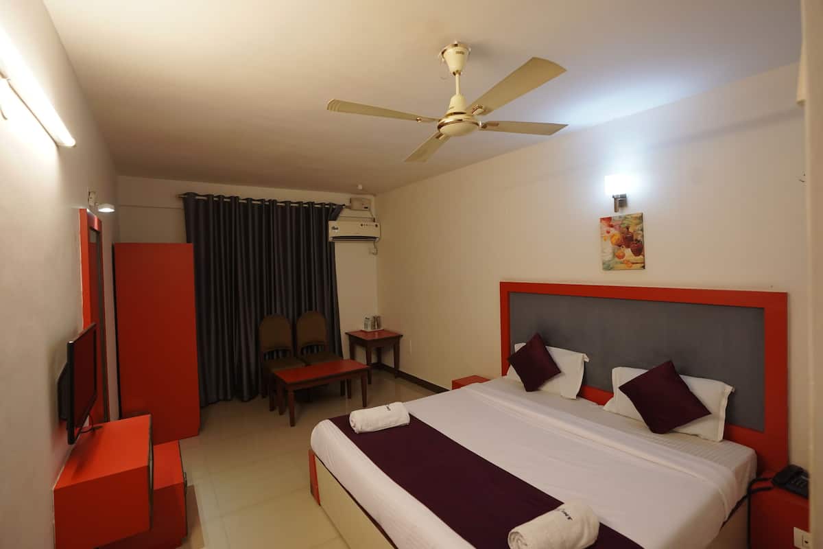 A hotel room with a bed, a desk, a chair, a TV, and a ceiling fan.