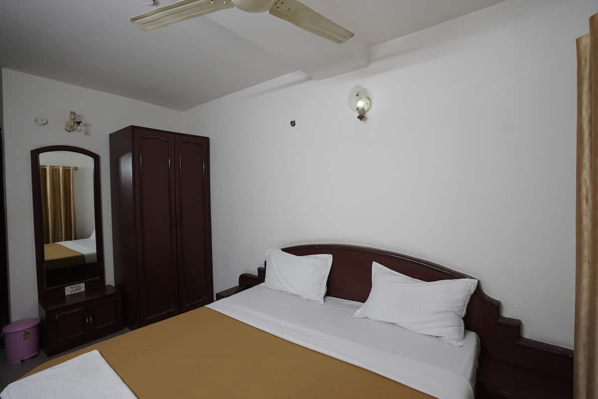A hotel room with a bed, a wardrobe, a mirror, and a ceiling fan.
