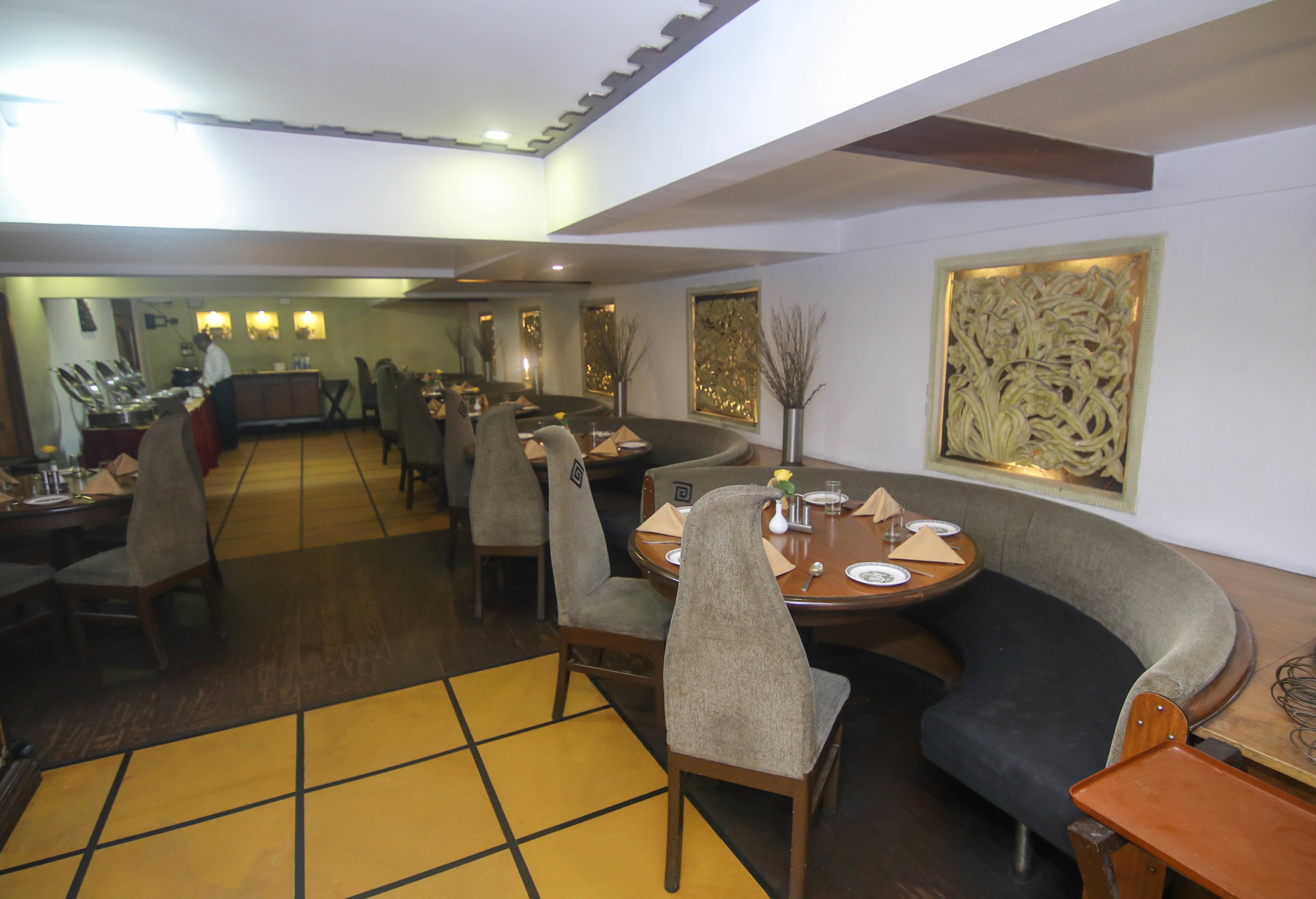A restaurant with a long counter, multiple tables, and chairs.