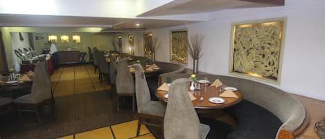 Un restaurante con una barra larga, varias mesas y sillas.