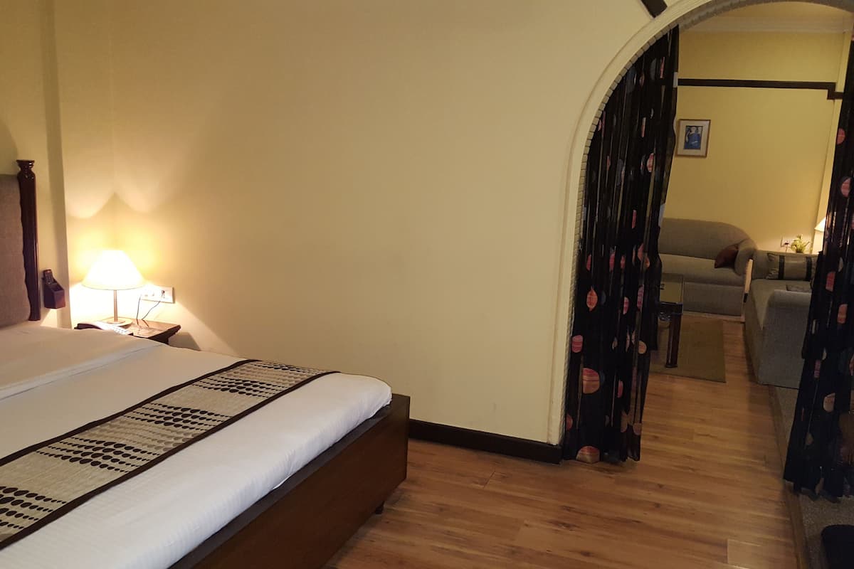 A hotel room with a bed, a nightstand, a lamp, a sofa, and a staircase.
