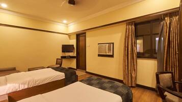 Quarto de hotel com duas camas, televisão, aparelho de ar condicionado e uma cadeira.