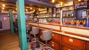 A bar with stools, shelves of bottles, and a Heineken sign. - Lytton Hotel (Kolkata)