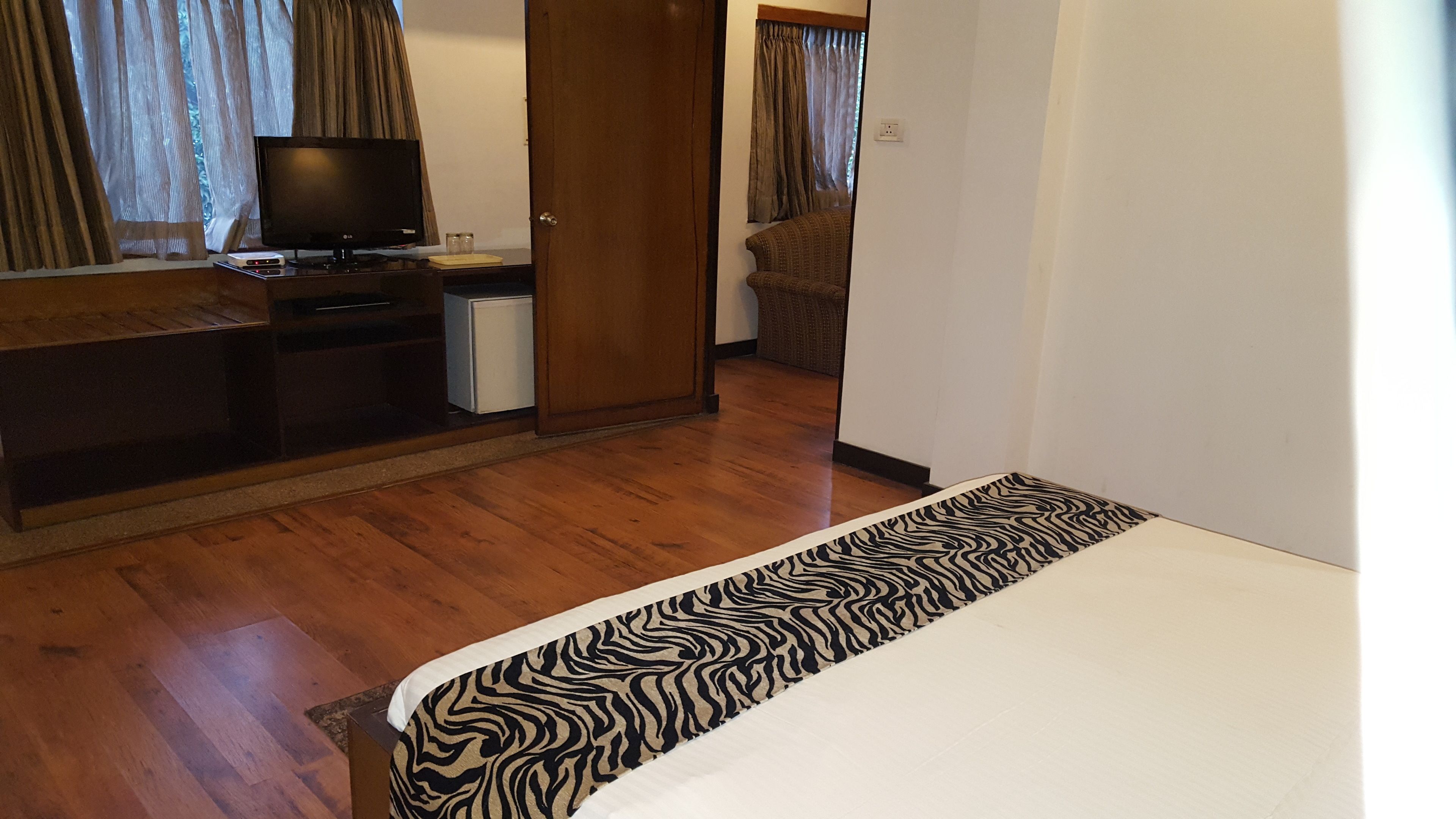Une chambre d’hôtel équipée d’un lit, d’un bureau avec un ordinateur, d’une télévision et d’un petit réfrigérateur.