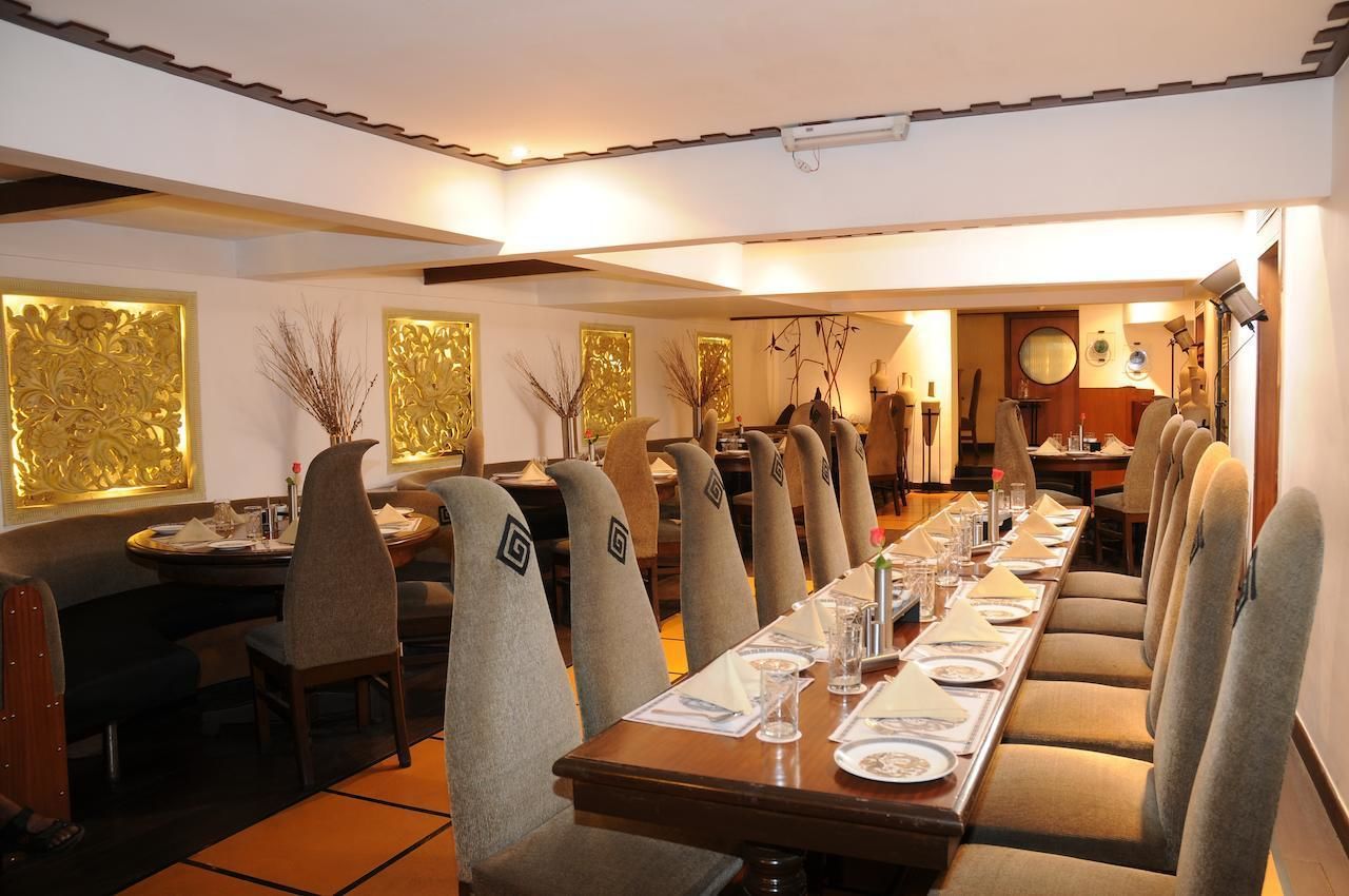 Una larga mesa de comedor con sillas, una araña y paneles decorativos en la pared.