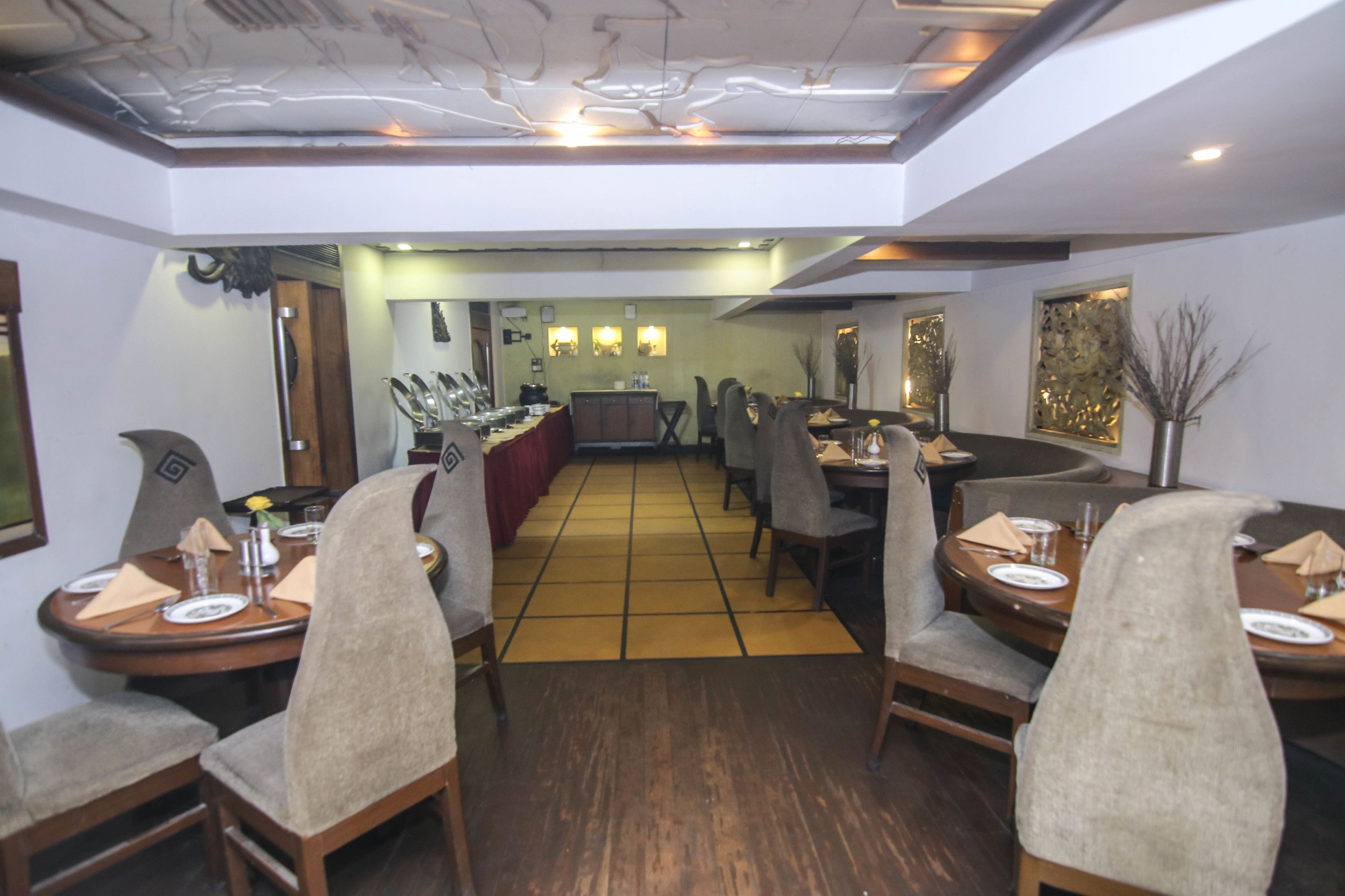 A restaurant with wooden tables and chairs, a tiled floor, and a central bar area.