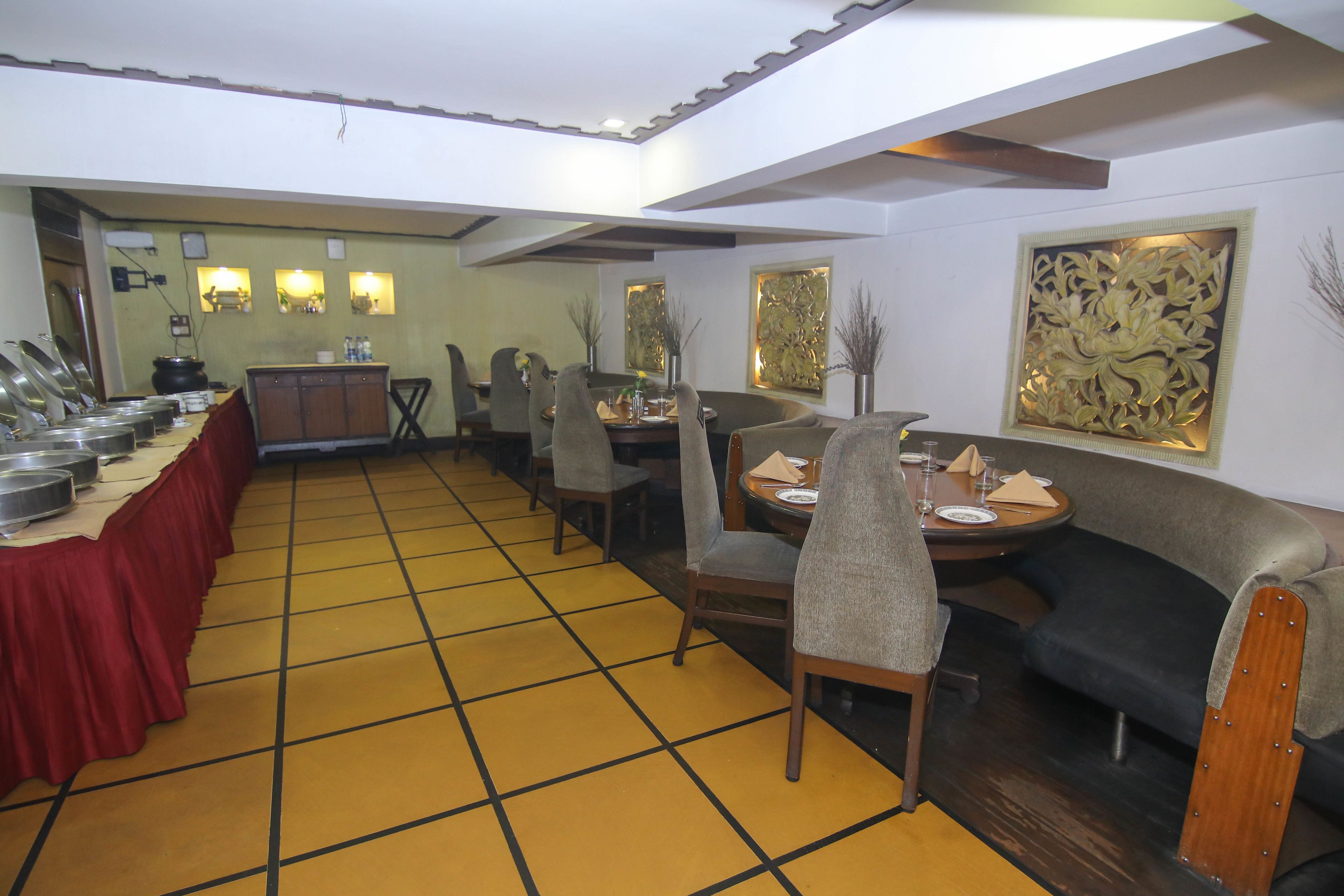 A dining area with a buffet setup, a sofa, and a decorative wall piece.