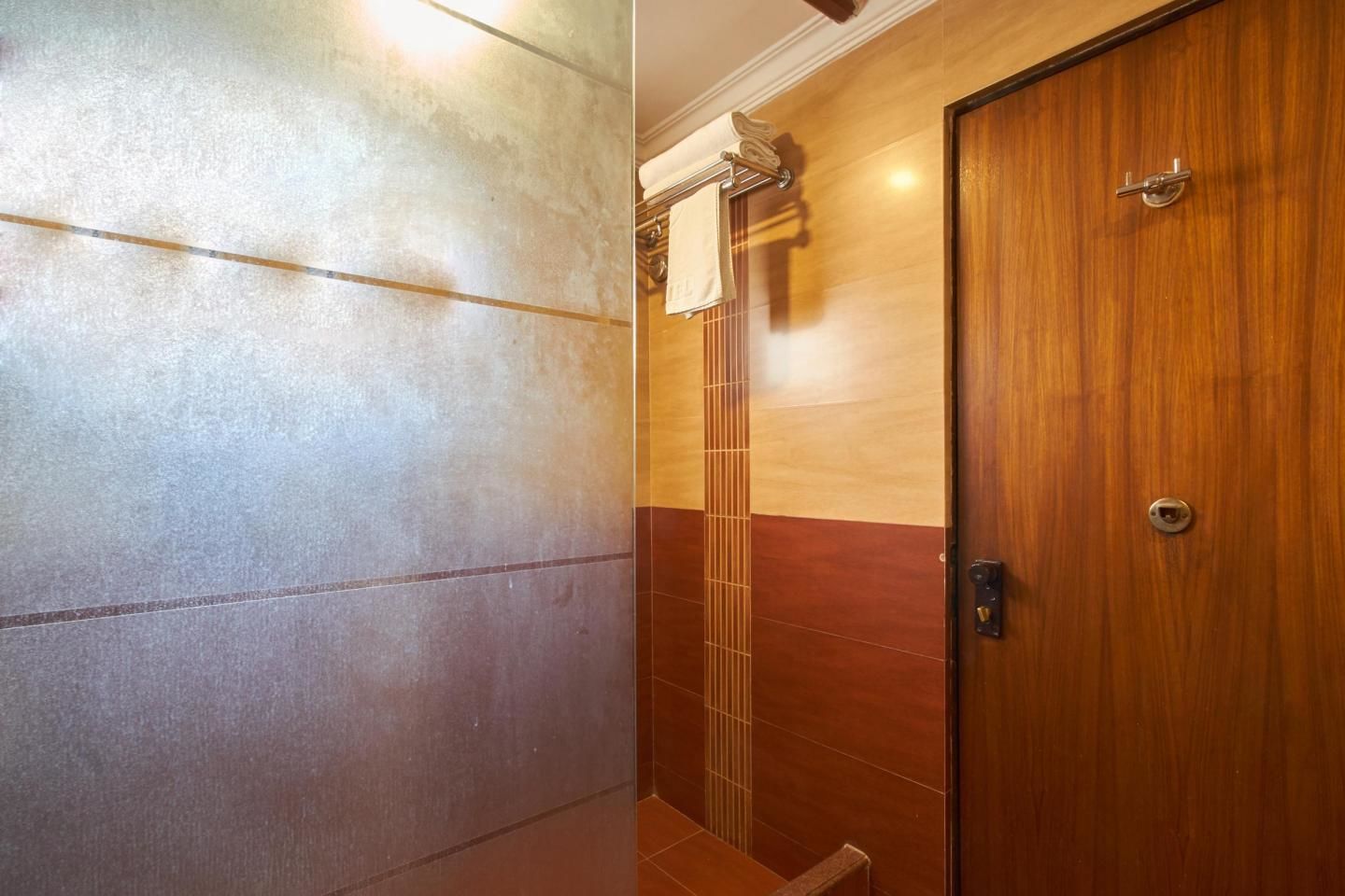 A bathroom with a tiled wall and a wooden door.