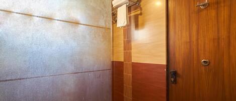 A bathroom with a tiled wall and a wooden door.