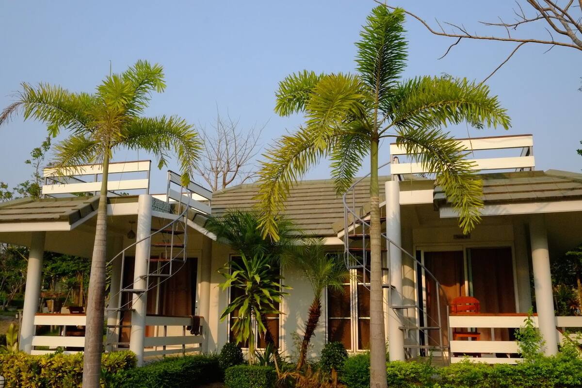 A modern building with a flat roof, large windows, and a covered outdoor area with benches.