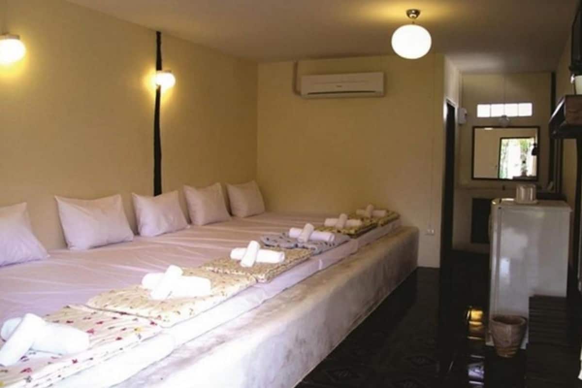 A hotel room with a large bed, a refrigerator, and an air conditioning unit.