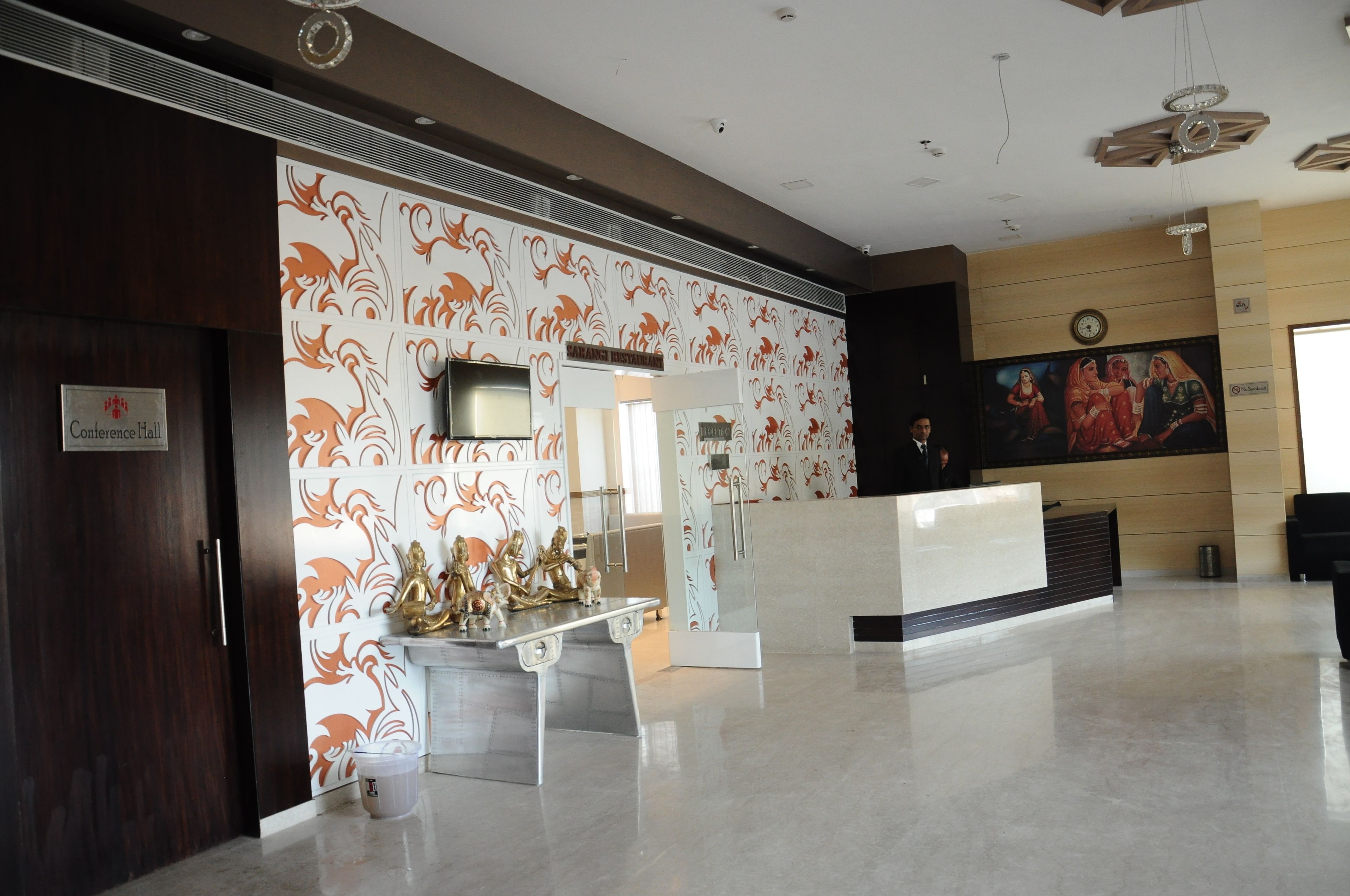 Un espace d’accueil au design moderne, comprenant un mur décoré d’un motif, un comptoir d’accueil et une horloge murale.