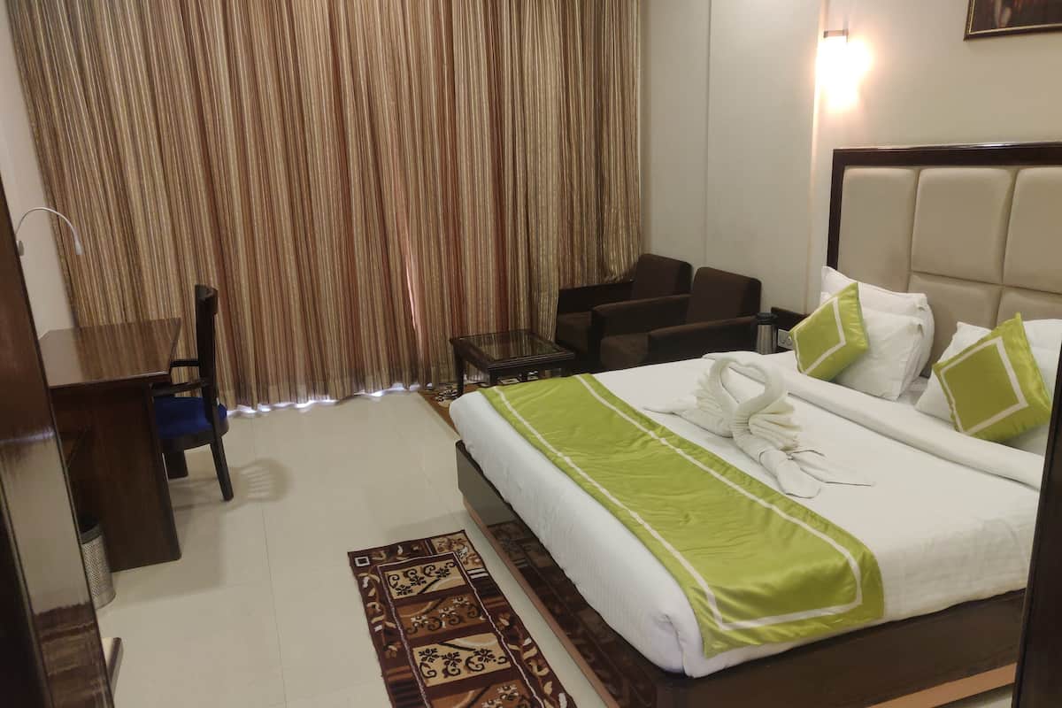 A hotel room with a large bed, a desk, a chair, and a coffee table.