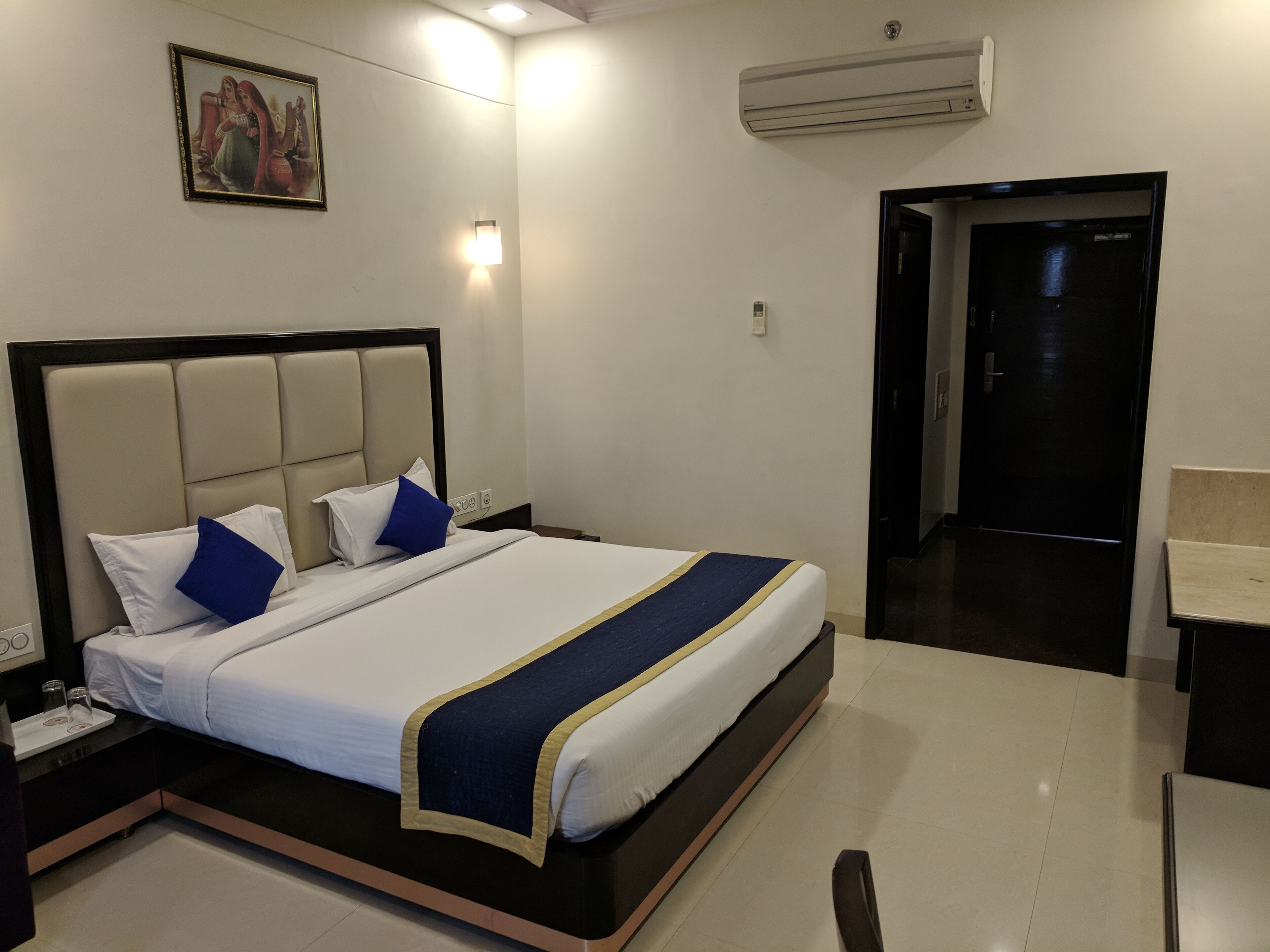 Hotelkamer met bed, nachtkastje, wandairconditioning en een deur naar de badkamer.