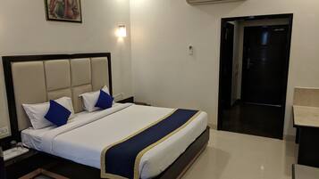 Hotelkamer met bed, nachtkastje, wandairconditioning en een deur naar de badkamer.