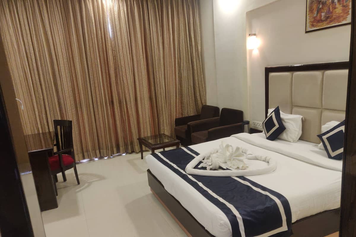 A hotel room with a bed, a desk, a chair, and a curtain.