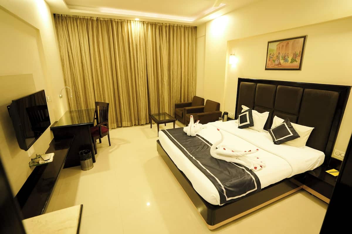 A hotel room with a large bed, a desk with a chair, a TV, and a painting on the wall.