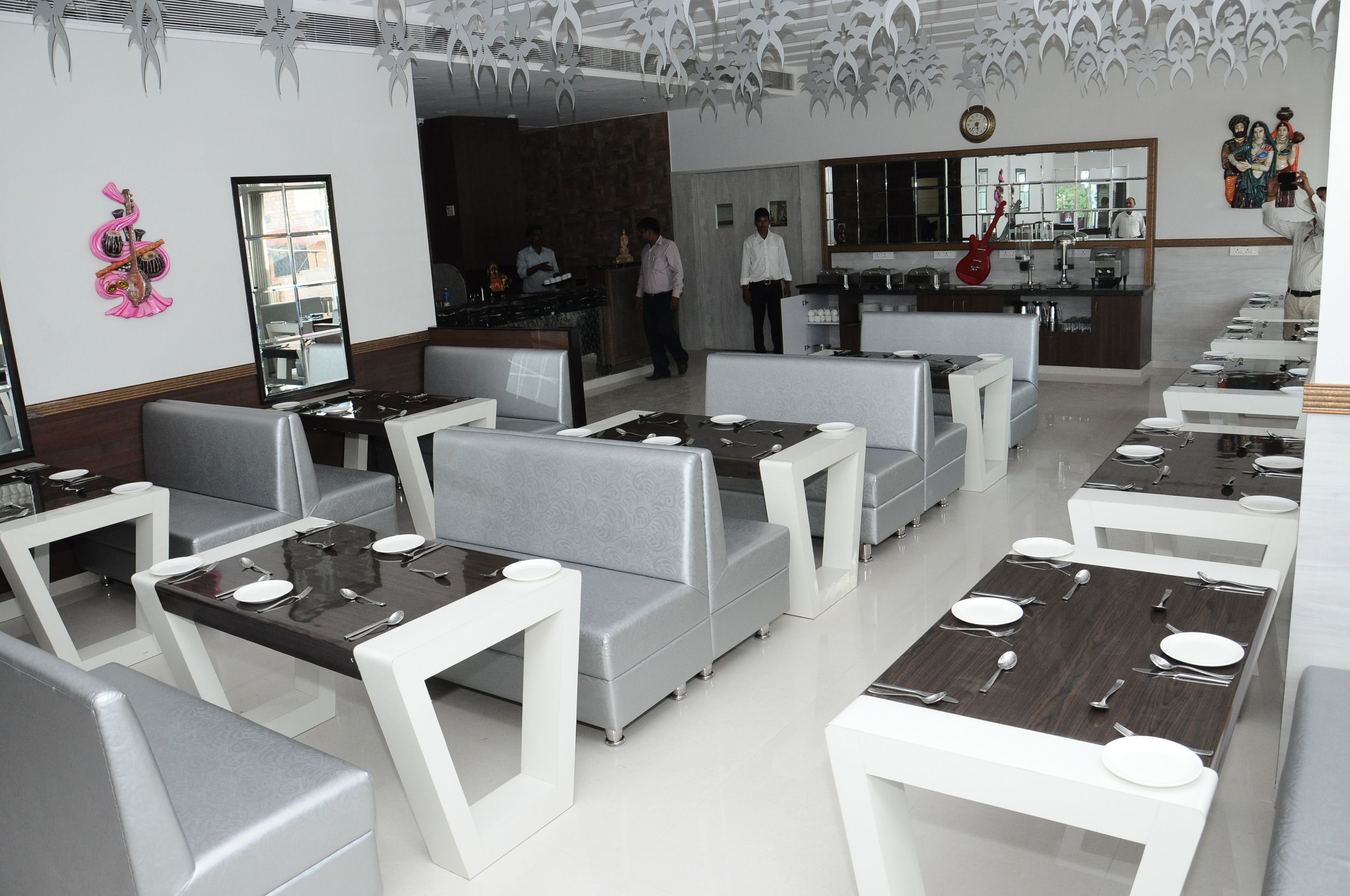 Un restaurante moderno con asientos blancos y grises, una barra central y arte decorativo en las paredes.