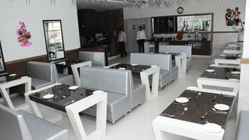 Un restaurante moderno con asientos blancos y grises, una barra central y arte decorativo en las paredes.