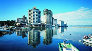 A waterfront cityscape with high-rise buildings and boats docked along the shore. - Kagaya (Nanao)