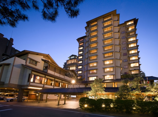 A multi-story hotel with a traditional architectural style, featuring a covered entrance area and a parking lot. - Kagaya (Nanao)