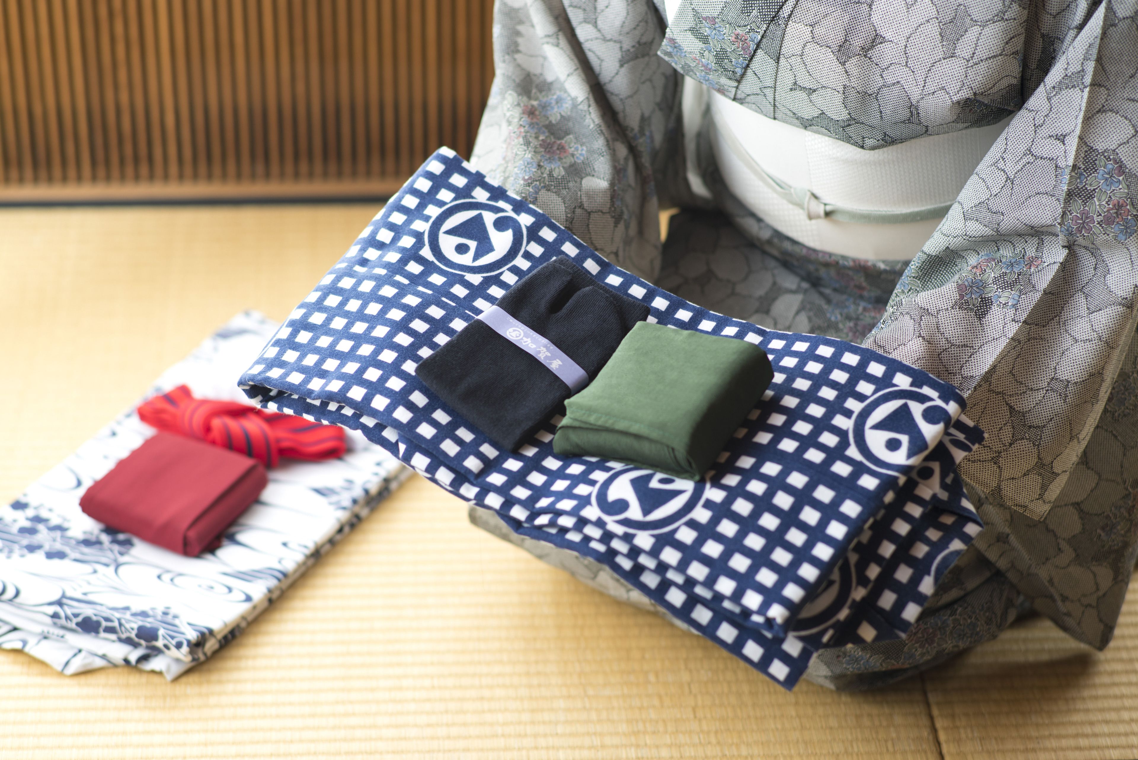 A traditional Japanese room with tatami flooring, a low table, and a futon bed with a patterned blanket.