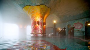 A spacious indoor pool with a mosaic ceiling and walls, featuring a central column and a large floral mural. - Kagaya (Nanao)