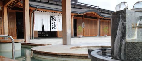 Un onsen japonès tradicional amb estructures de fusta i una font termal de pedra.