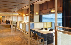 A modern restaurant with wooden furniture, a view of the water, and a balcony. - Kagaya (Nanao)