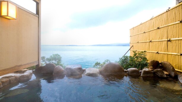 A hot spring bath with clear water, rocks, and a bamboo fence. - Aenokaze (Nanao)