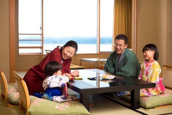 Una habitación japonesa tradicional con suelo de tatami, una mesa baja y vistas al mar a través de amplios ventanales.