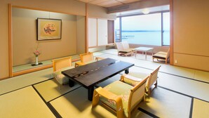 A tatami mat room with a low table, chairs, and a view of the sea. - Aenokaze (Nanao)