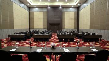 A conference room with multiple tables, chairs, and a red carpeted floor.