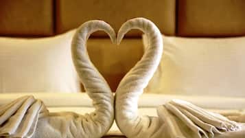 A bed with towels arranged in a heart shape.
