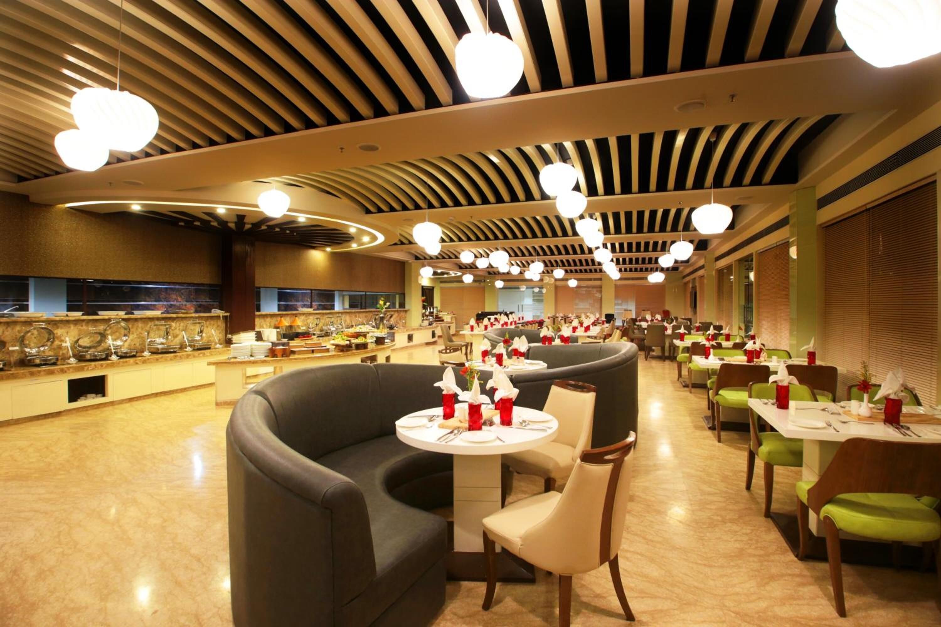 Un restaurant moderne doté d’un espace salon aux lignes courbes, de plusieurs tables et d’une variété de luminaires.