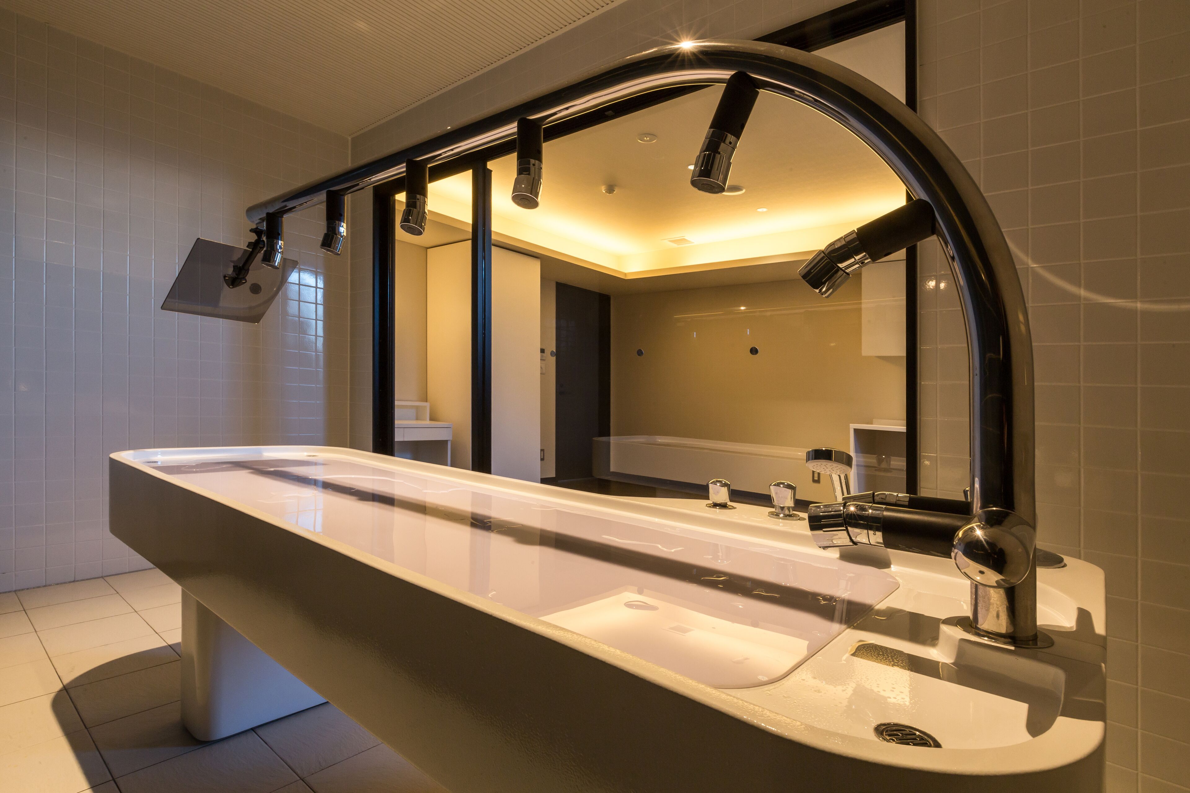 A modern bathroom with a large mirror, a sink, and a shower.