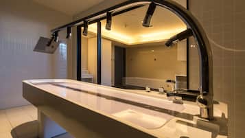 A modern bathroom with a large mirror, a sink, and a shower.