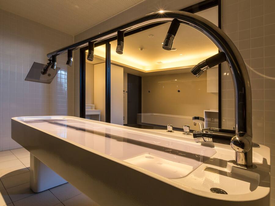 A modern bathroom with a large mirror, a sink, and a shower.