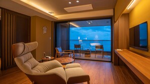 A modern hotel room with a large window, a comfortable seating area, and a flat-screen TV. - Amane Resort Gahama (Beppu)