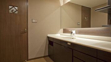 A modern bathroom with a wooden door, a white sink, and a large mirror.