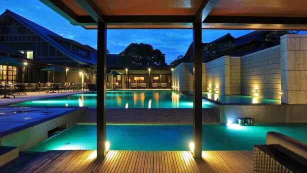 A pool area with a wooden deck, lounge chairs, and a covered seating area. - Amane Resort Gahama (Beppu)
