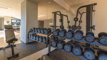 Un gimnasio con equipo de levantamiento de pesas y mancuernas.
