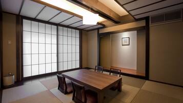 A traditional Japanese-style room with tatami flooring, a wooden table, and shoji screens.