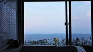 A room with a large window overlooking the sea, a tiled floor, and a bench. - Amane Resort Gahama (Beppu)