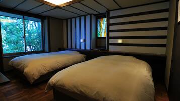 A room with two beds, a large window, and a stained glass window.