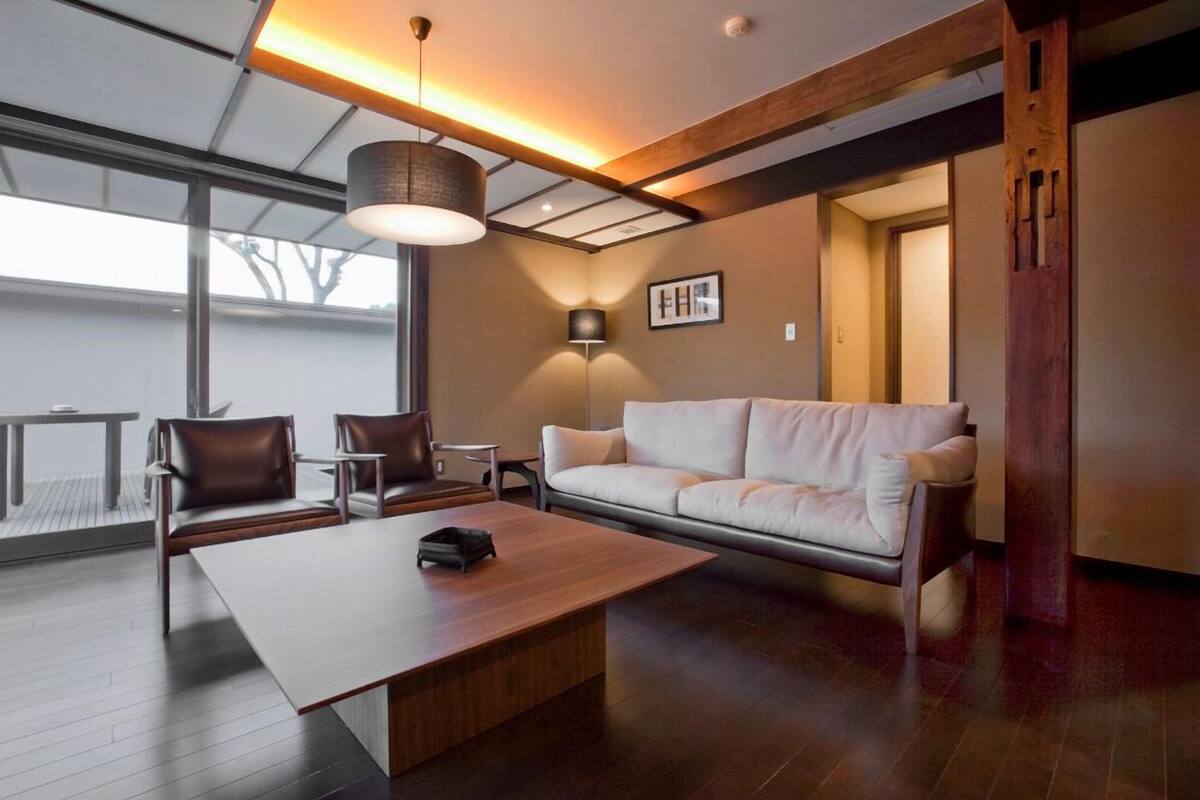A modern living room with a sofa, chairs, a coffee table, and a pendant light.