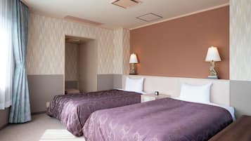 A hotel room with two beds, a nightstand, a lamp, and a window with curtains.