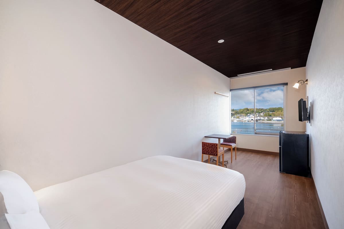 Ett modernt hotellrum med en stor säng, ett skrivbord och utsikt över havet.