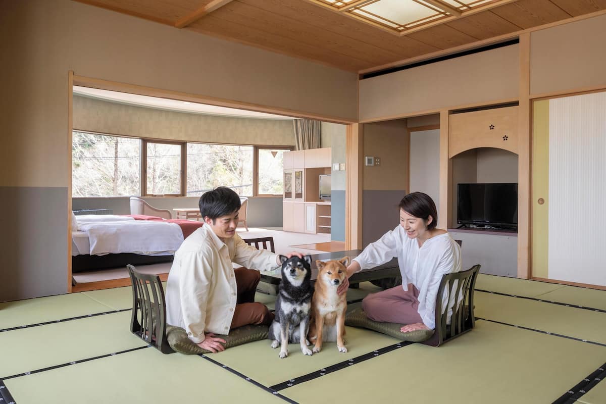 Ett traditionellt japanskt rum med tatamimattor på golvet, en futonmadrass, en tv och en skjutdörr.