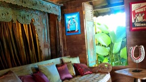 Ein traditionelles Holzsofa mit bunten Kissen, einem dekorativen Spiegel und einem gerahmten Bild an der Wand.